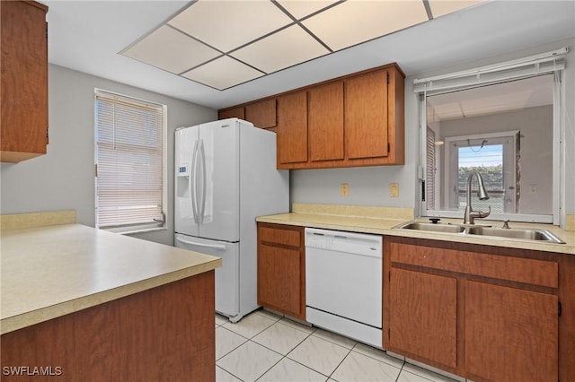 kitchen featuring light countertops, white appliances, a sink, and brown cabinets