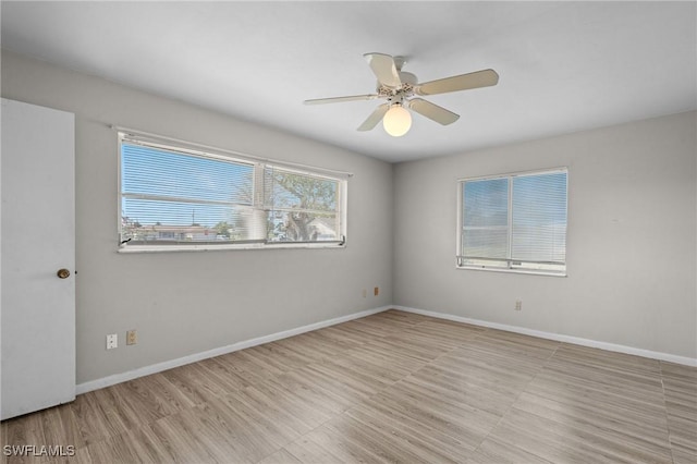 spare room featuring wood finished floors, a ceiling fan, and baseboards