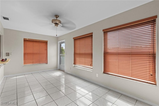 spare room with light tile patterned floors, baseboards, visible vents, and a ceiling fan