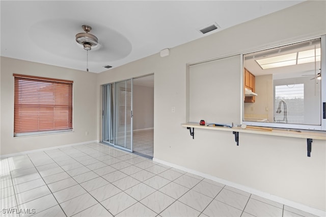 empty room with visible vents, ceiling fan, baseboards, and light tile patterned floors