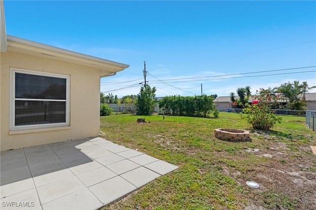 view of yard featuring an outdoor fire pit, fence, and a patio