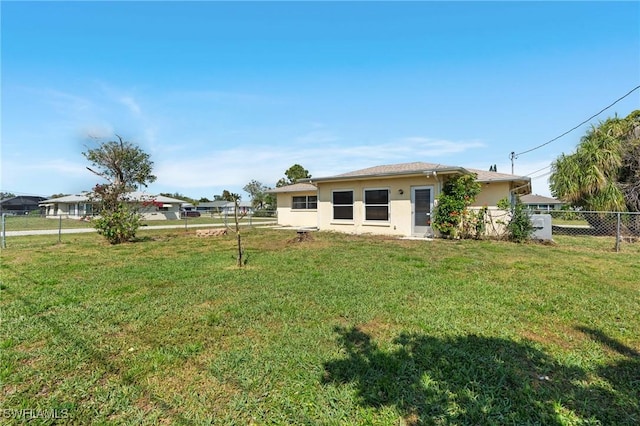 back of house featuring stucco siding, fence, and a yard