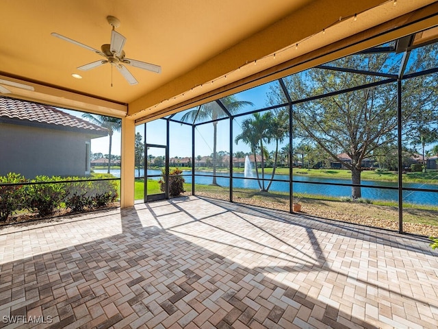 unfurnished sunroom with ceiling fan and a water view