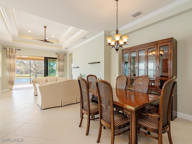 dining space with light tile patterned flooring, visible vents, baseboards, ornamental molding, and a raised ceiling