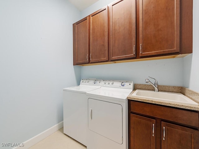 laundry area with cabinet space, baseboards, washer and clothes dryer, and a sink