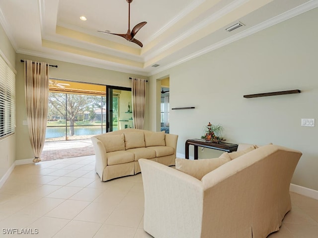 living area with light tile patterned floors, visible vents, ornamental molding, a water view, and a tray ceiling