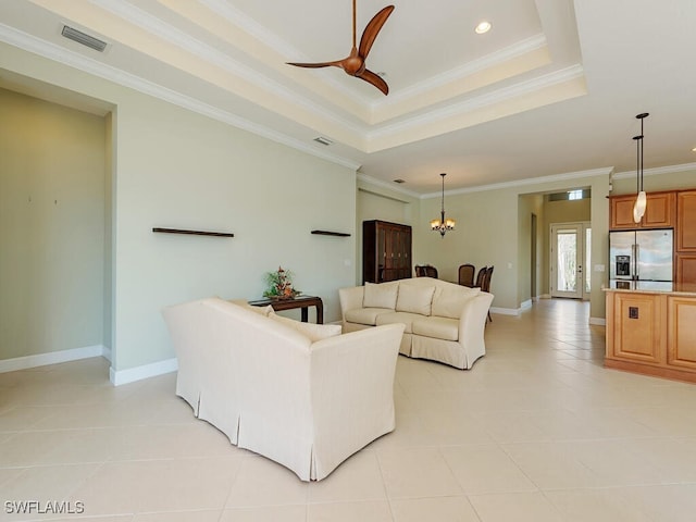 living area featuring light tile patterned floors, a tray ceiling, ornamental molding, and visible vents