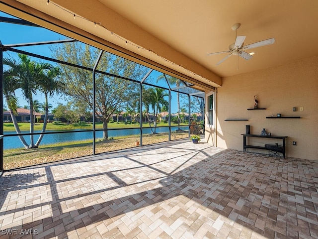 unfurnished sunroom featuring a water view and a ceiling fan