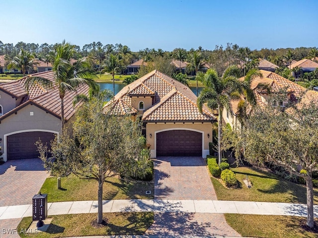 mediterranean / spanish home with an attached garage, a front yard, decorative driveway, and stucco siding