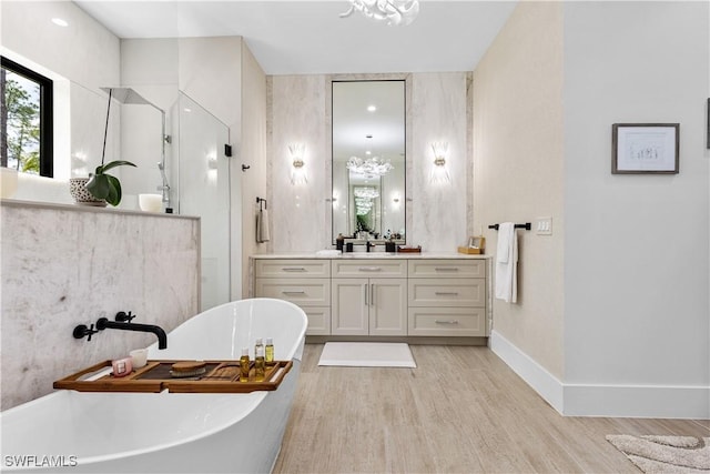 full bathroom featuring a freestanding bath, vanity, wood finished floors, baseboards, and a walk in shower