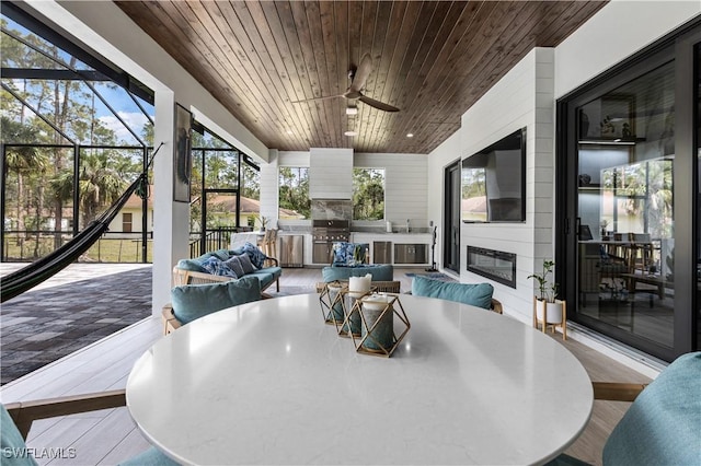 sunroom with wood ceiling, a fireplace, and ceiling fan