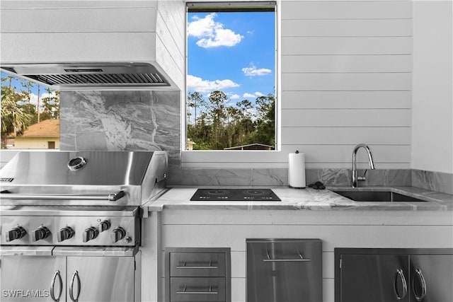 kitchen with light stone counters, refrigerator, a sink, and under cabinet range hood