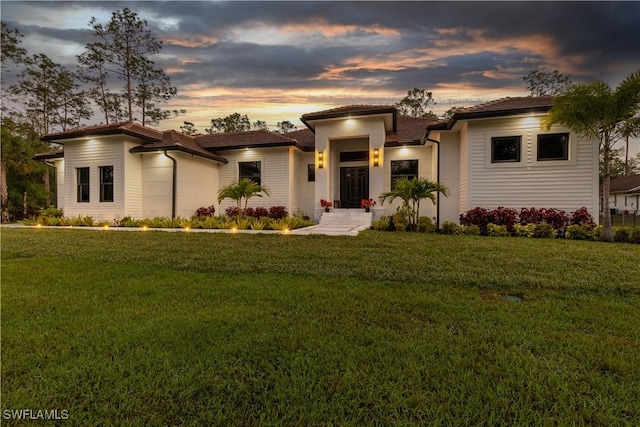 view of front of property featuring a garage, driveway, and a lawn