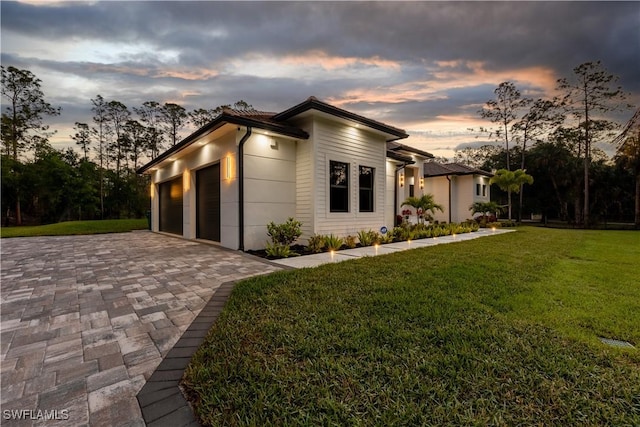 view of home's exterior with a garage, decorative driveway, and a lawn