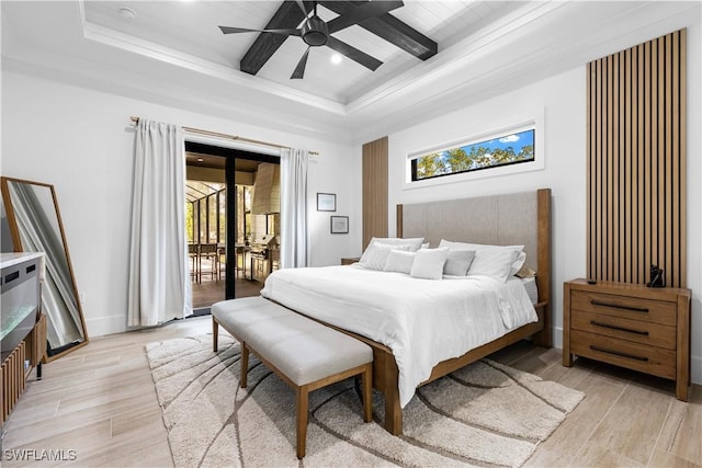 bedroom with light wood-type flooring, access to outside, and a raised ceiling