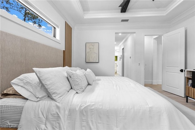 bedroom with visible vents, light wood-type flooring, beam ceiling, ensuite bath, and crown molding