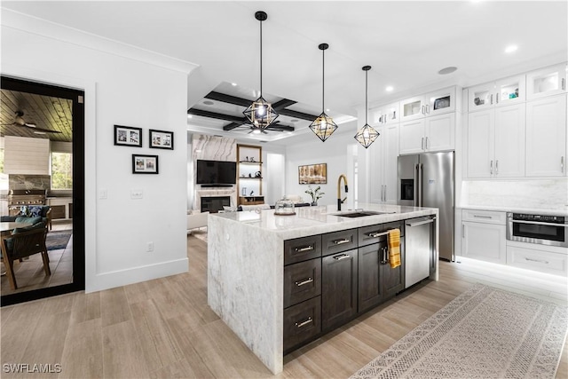 kitchen featuring white cabinets, ceiling fan, stainless steel appliances, a fireplace, and a sink