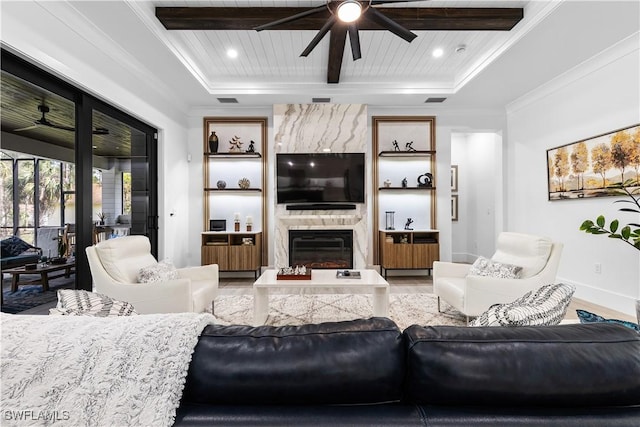 living area with a premium fireplace, ornamental molding, a ceiling fan, and beamed ceiling