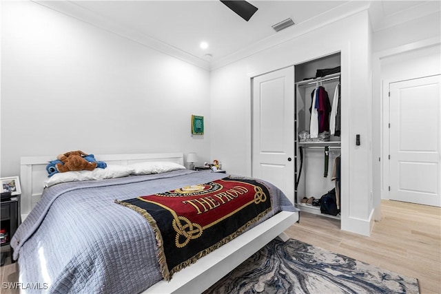 bedroom with a ceiling fan, visible vents, a closet, light wood finished floors, and crown molding