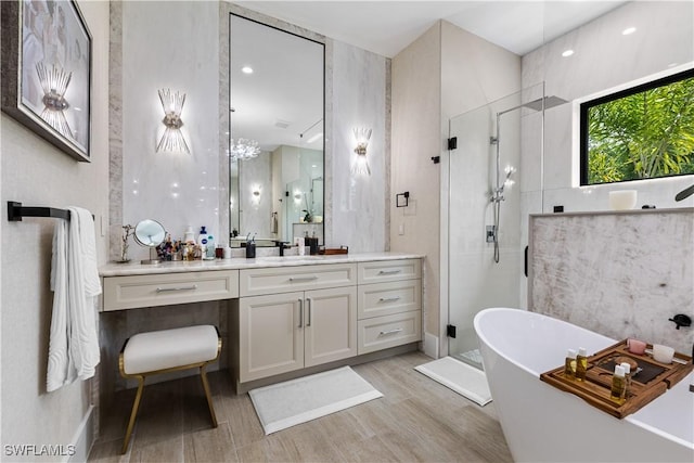 full bath with a stall shower, a freestanding tub, wood finished floors, and vanity