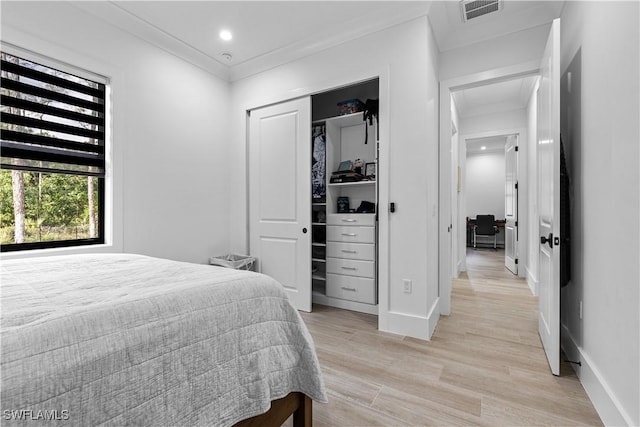 bedroom with ornamental molding, light wood-type flooring, visible vents, and baseboards