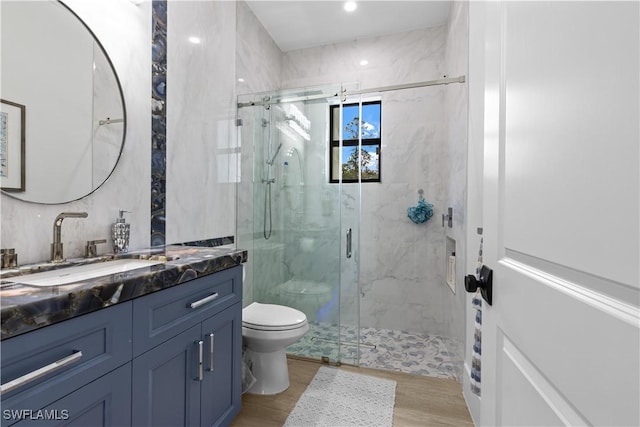 full bathroom featuring a marble finish shower, vanity, toilet, and wood finished floors