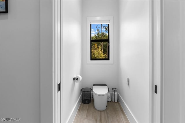 bathroom with toilet, baseboards, and wood finished floors