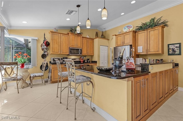 kitchen featuring stainless steel appliances, visible vents, ornamental molding, a kitchen bar, and decorative light fixtures