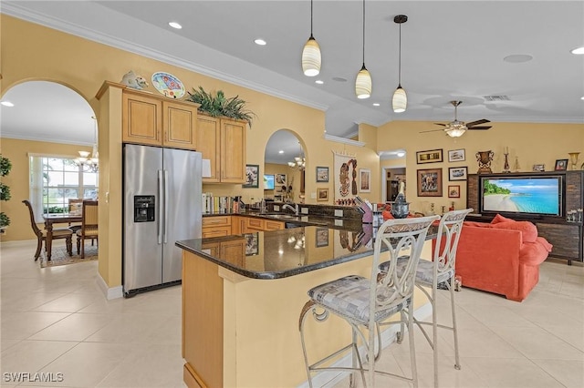 kitchen with arched walkways, stainless steel refrigerator with ice dispenser, a sink, and ornamental molding