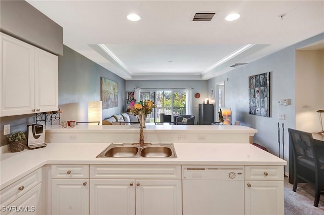 kitchen featuring light countertops, open floor plan, white cabinets, white dishwasher, and a peninsula