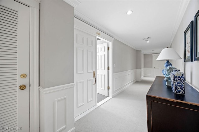 hallway featuring carpet floors, a wainscoted wall, recessed lighting, a decorative wall, and ornamental molding