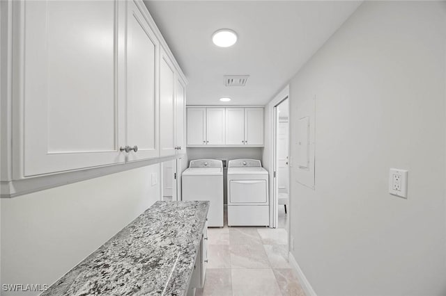 washroom with visible vents, washer and clothes dryer, cabinet space, and baseboards