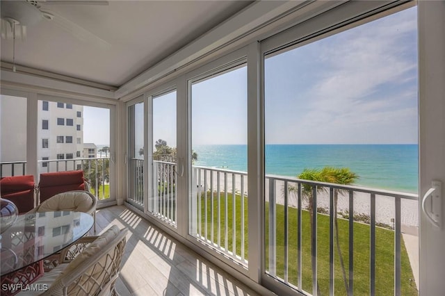 sunroom featuring a beach view and a water view