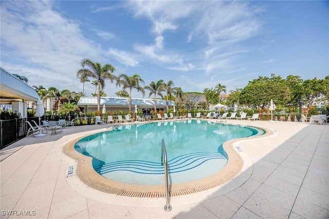 community pool with a patio area and fence