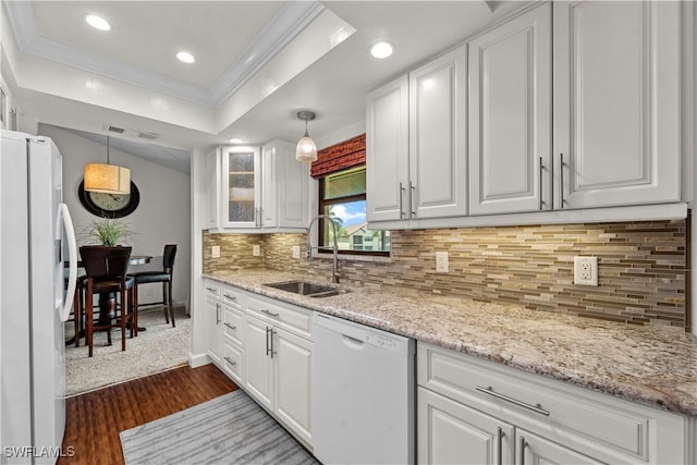 kitchen featuring a tray ceiling, white appliances, a sink, and white cabinets