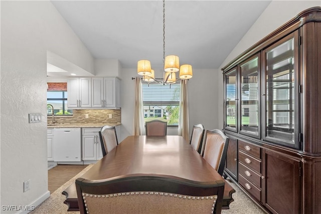 dining space with lofted ceiling, a healthy amount of sunlight, baseboards, and an inviting chandelier