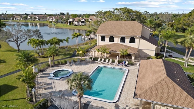 pool featuring a community hot tub, a patio area, a water view, and fence