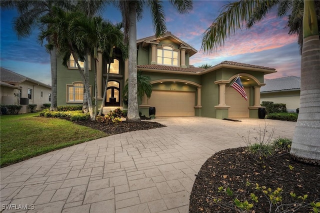 mediterranean / spanish home with a yard, french doors, decorative driveway, and stucco siding