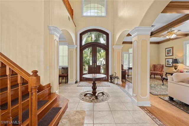 entrance foyer featuring light tile patterned floors, decorative columns, arched walkways, stairway, and french doors