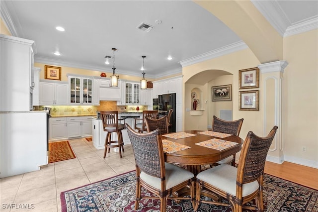 dining area with arched walkways, light tile patterned floors, recessed lighting, visible vents, and crown molding