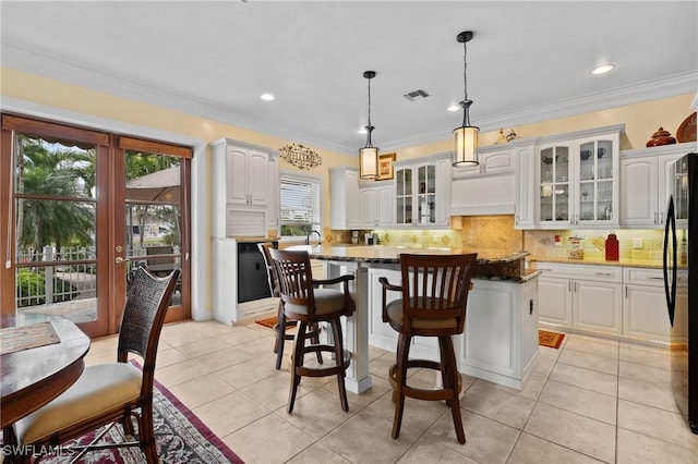 kitchen with a kitchen island, visible vents, white cabinetry, french doors, and backsplash