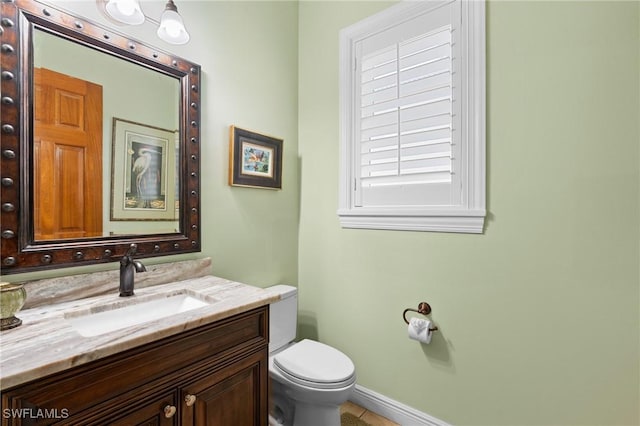 bathroom with vanity, toilet, and baseboards