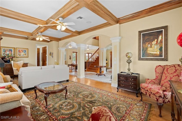 living room with arched walkways, decorative columns, visible vents, coffered ceiling, and stairs