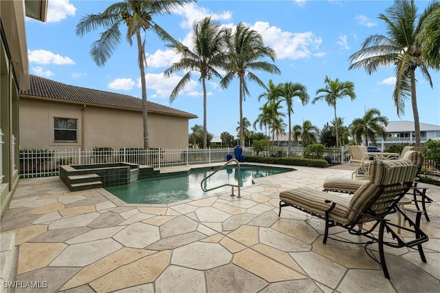 view of pool featuring a patio, fence, and a pool with connected hot tub