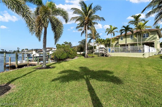 view of yard with a water view, a boat dock, boat lift, and fence