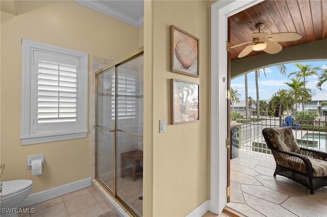 bathroom featuring baseboards, toilet, tile patterned flooring, crown molding, and a shower stall