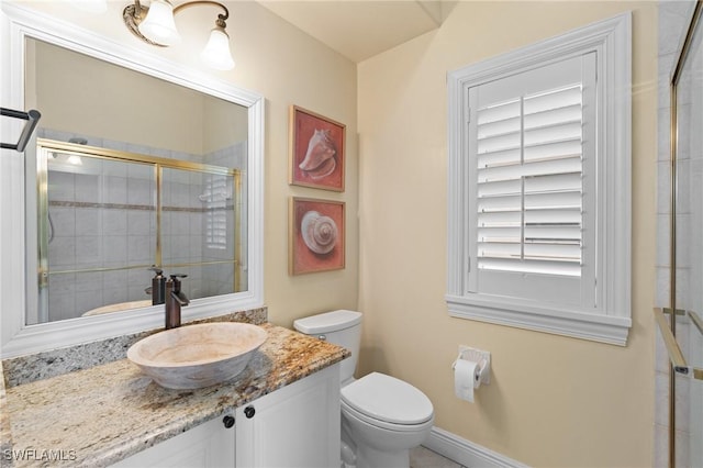 full bathroom with baseboards, tiled shower, vanity, and toilet