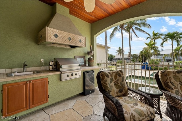 view of patio featuring a sink, a ceiling fan, fence, exterior kitchen, and grilling area