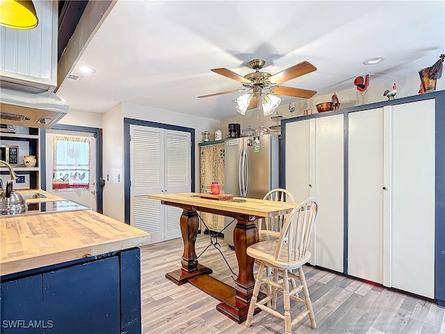 interior space featuring light wood finished floors, butcher block countertops, freestanding refrigerator, and black electric cooktop