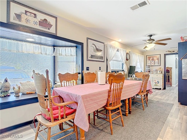 dining room featuring light wood finished floors, ceiling fan, visible vents, and baseboards